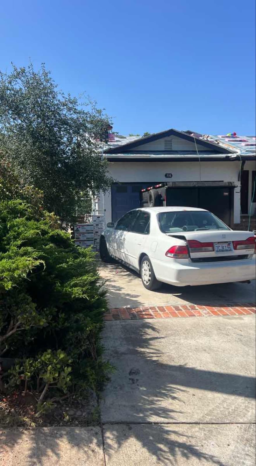 White sedan parked in a residential driveway with packages staged for pickup — the kind of light-duty car courier run Curri dispatches same-day for documents, parts, and small loads