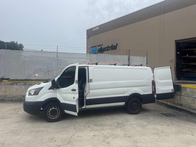 White Ford Transit cargo van with side door open at an industrial supplier dock for a same-day Curri pickup