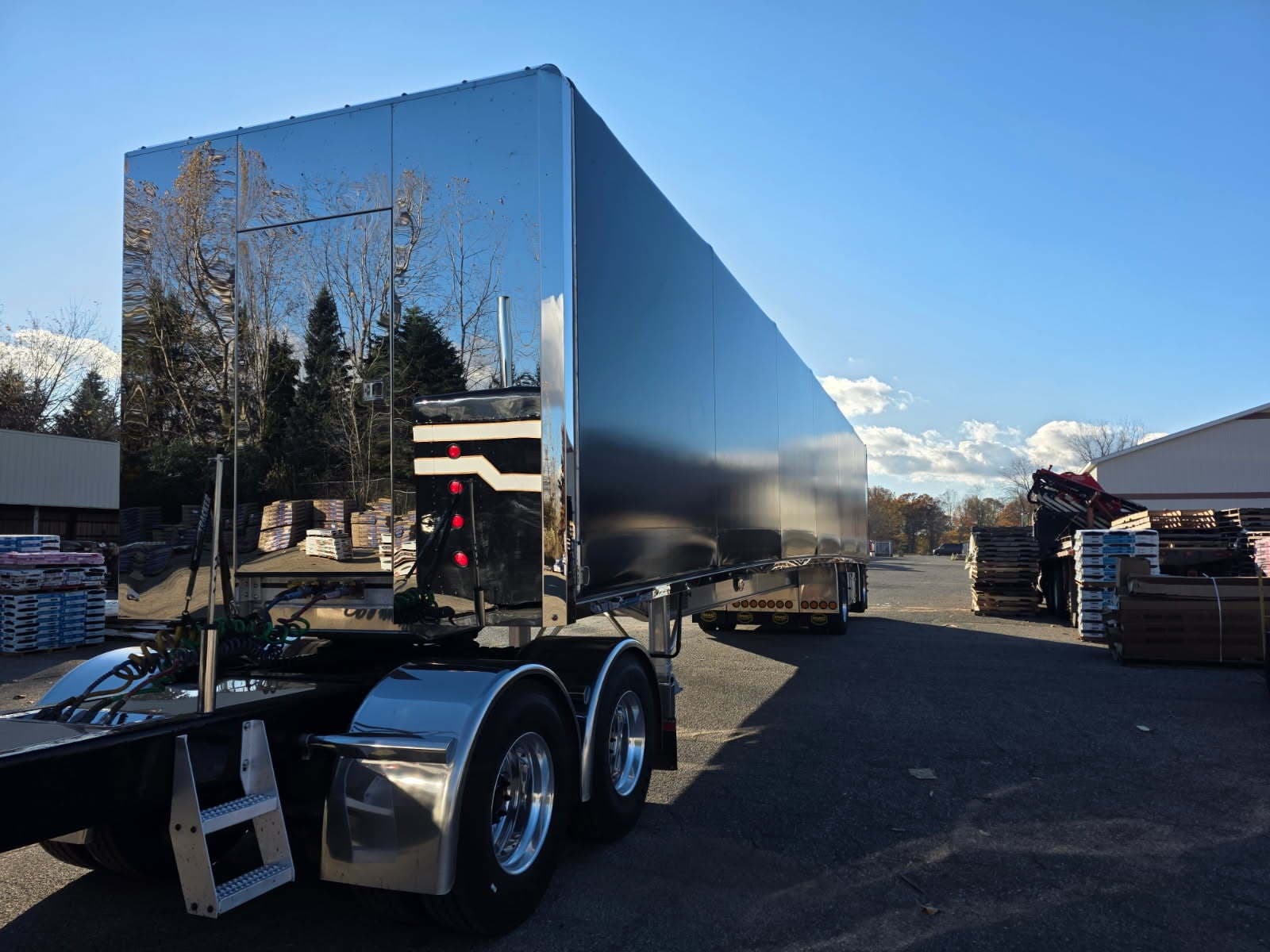 Chrome Curri dry van semi-tractor with a polished mirror-finish enclosed trailer staged at a lumber yard for a full truckload pickup