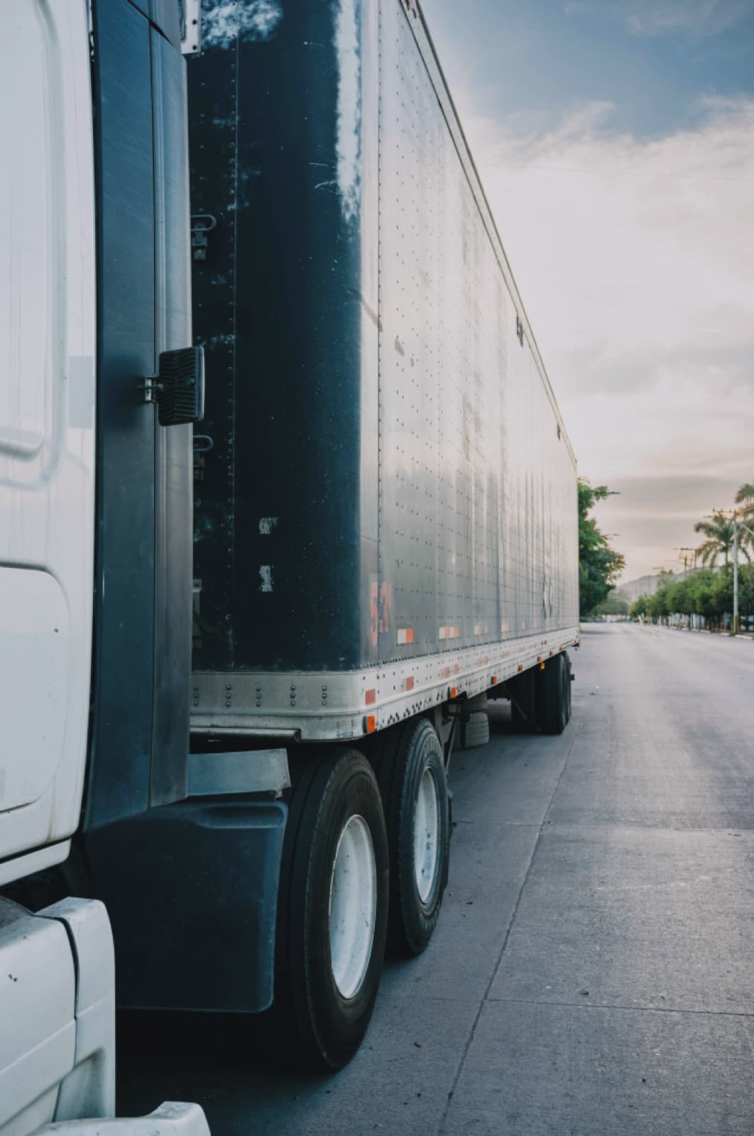 Side view of a white dry van semi-trailer rolling down the highway on a long-haul Curri freight route