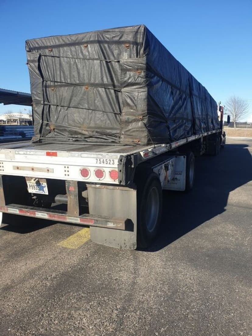 Tarped flatbed load strapped to a Curri semi for a long-haul delivery
