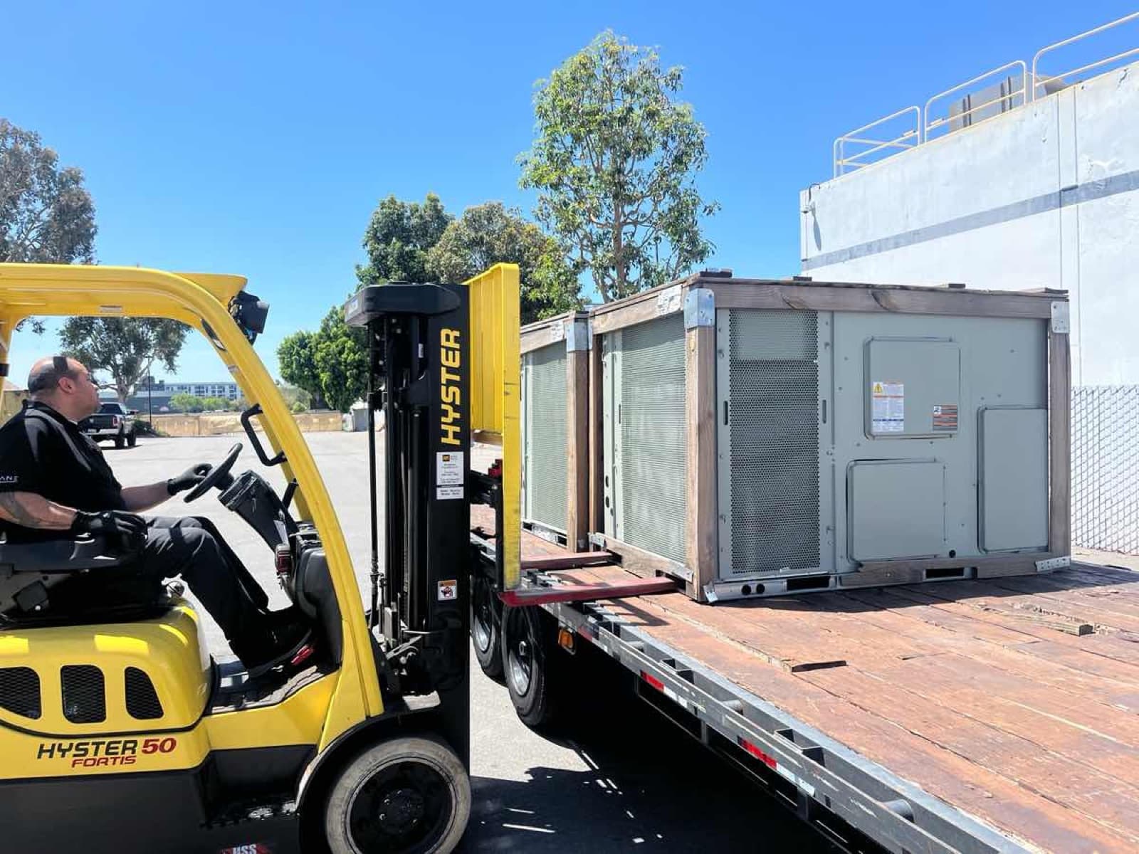 Yellow Hyster forklift loading an HVAC unit onto a Curri flatbed for a same-day Moffett delivery
