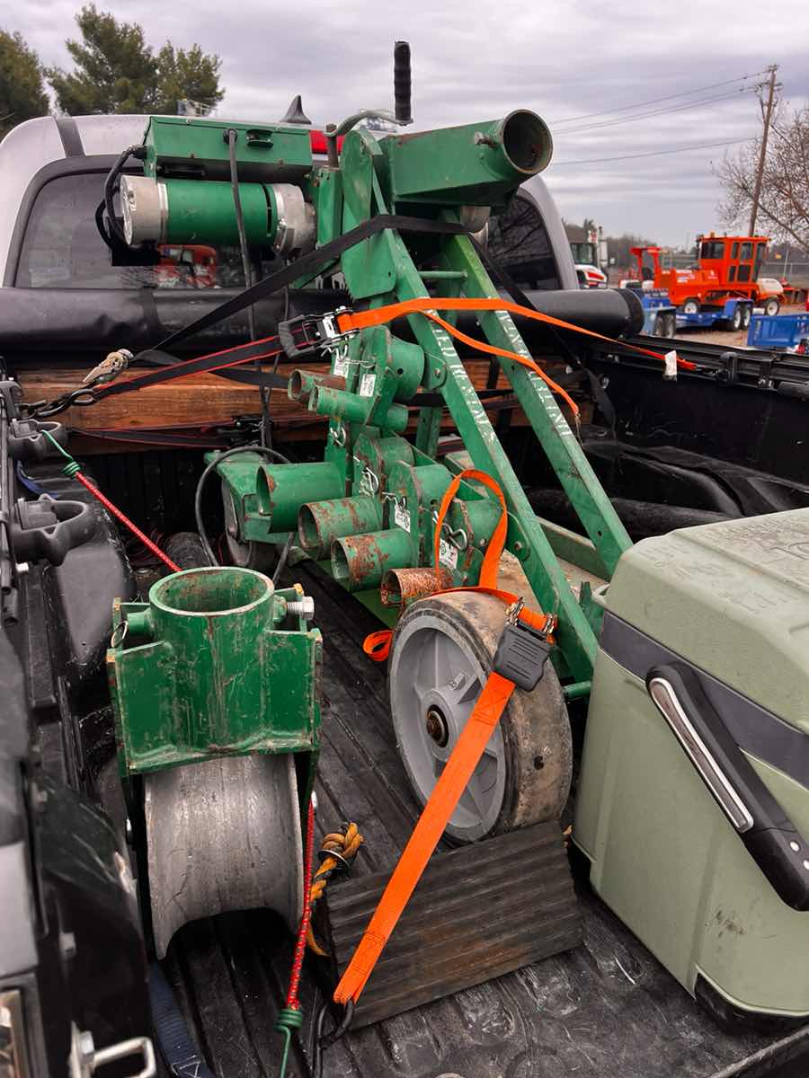 Pickup truck bed loaded with green plumbing equipment and conduit strapped down for a Curri same-day delivery