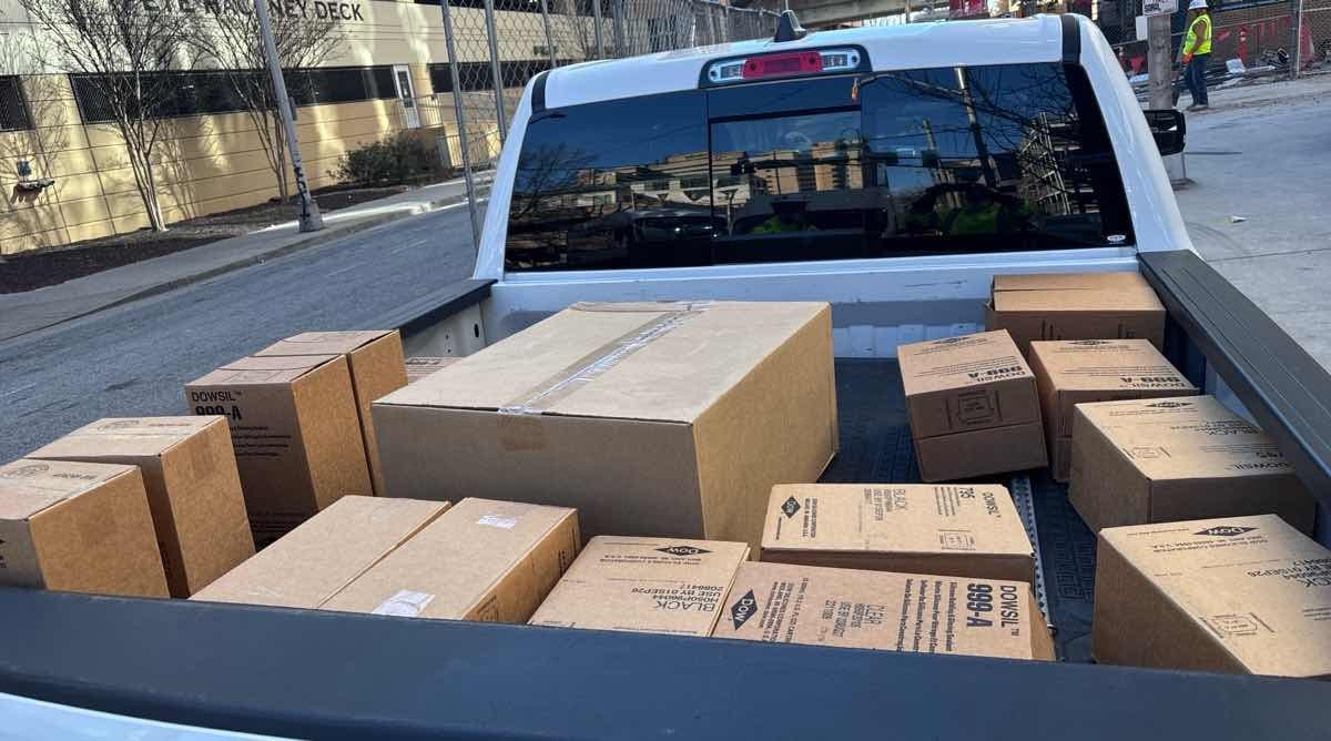 White pickup truck bed loaded with DOWSIL silicone boxes for a Curri same-day supply pickup