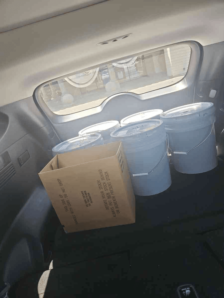 SUV interior loaded with paint pails and a parts box for a Curri same-day supply route