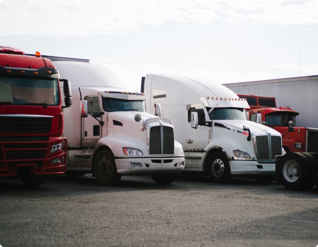 Row of red and white LTL freight trucks staged at a distribution terminal — Curri's national less-than-truckload carrier network with 85+ vetted carriers