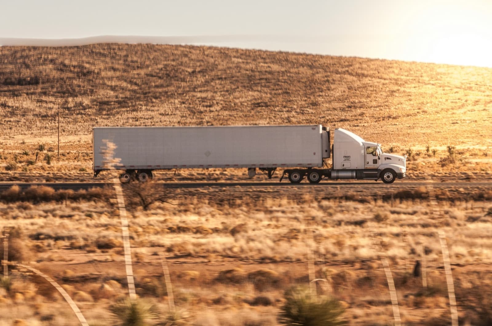 Curri LTL freight truck hauling pallets across a golden highway at dusk — less-than-truckload shipping built for modern logistics workflows